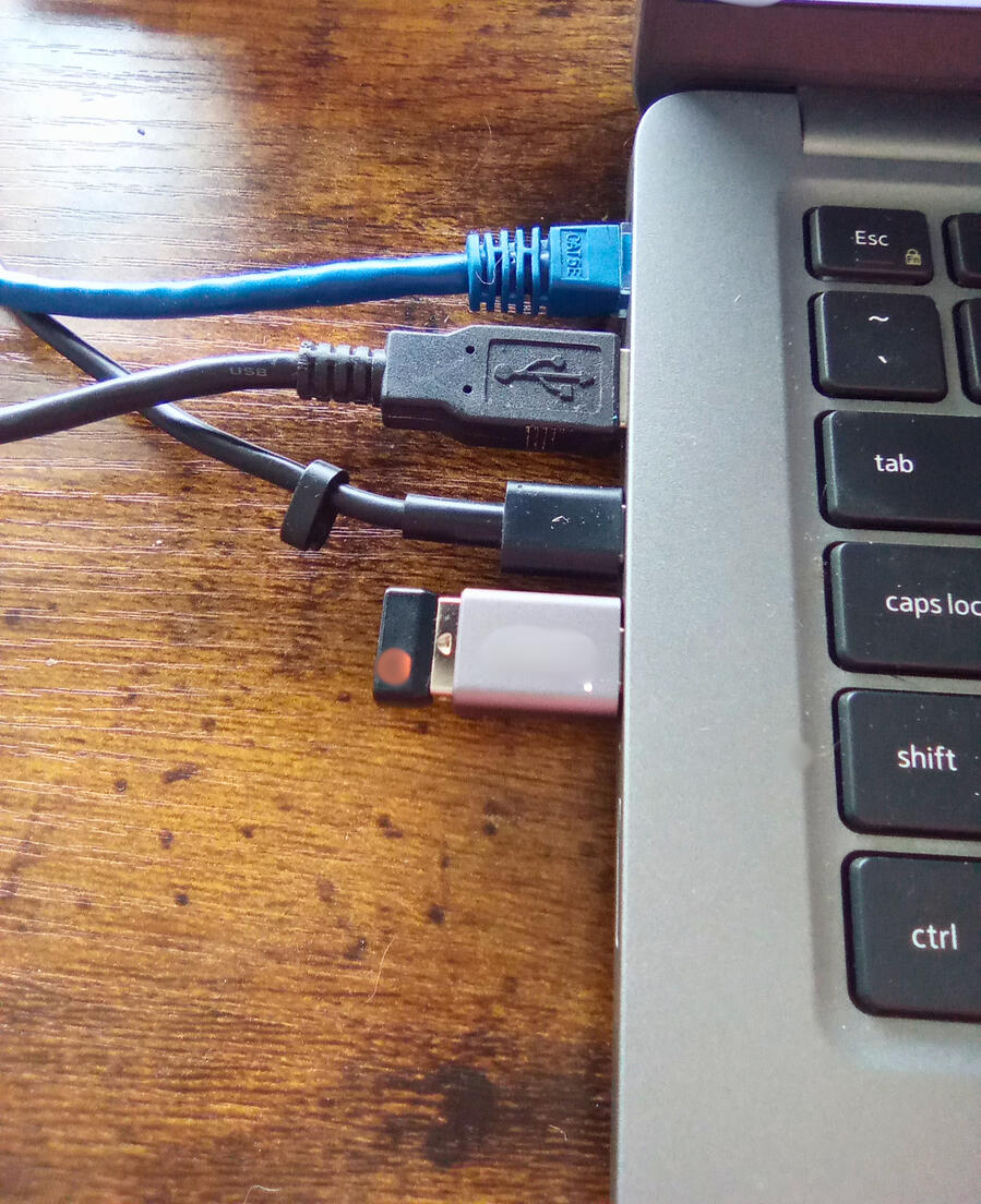 Laptop parts with ethernet and USB cables connected, resting on a wooden surface.